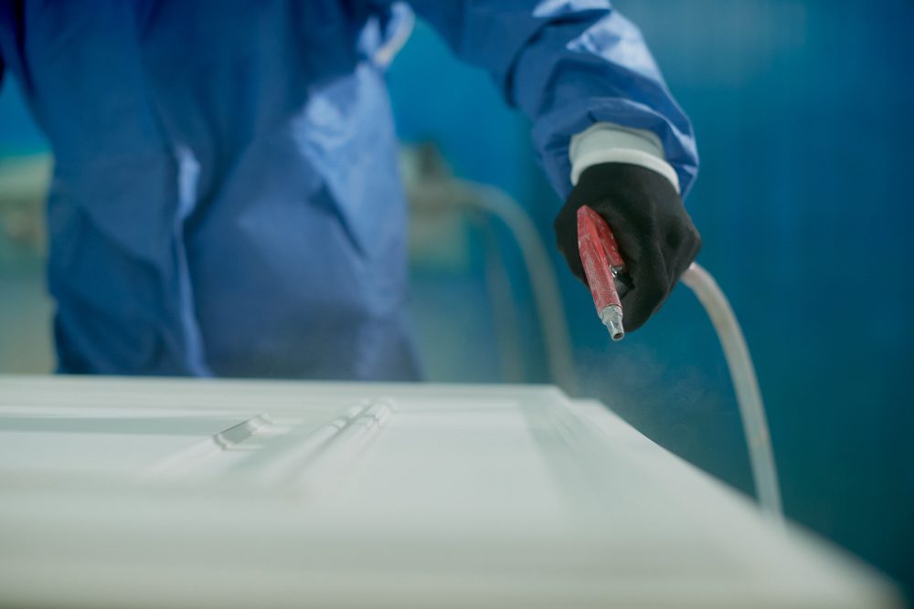 Person in protective suit using a spray gun to paint